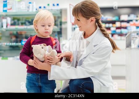 Apotheker Frau mit Kind Kunden und ihre Plüsch Spielzeug in der Pharmazie Stockfoto