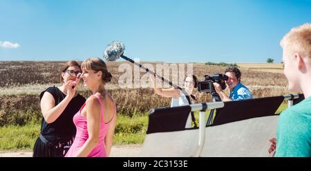 Film- oder Filmset mit Modell, Mikrofon und Assistent während einer Produktion Stockfoto