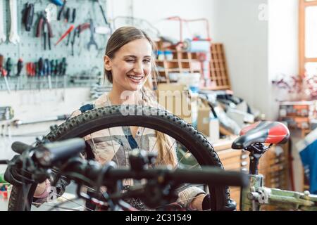 Sehr glücklich Fahrradmechaniker Frau durch das Rad Fahrrad suchen Stockfoto