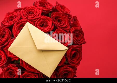 Liebesbrief und Blumenlieferservice am Valentinstag, luxuriöser Strauß roter Rosen und Kartenumschläge auf rotem Hintergrund Stockfoto