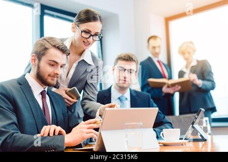 Ein Team von Geschäftsleuten, das an einer Präsentation arbeitet und Bücher und Computerbildschirme betrachtet Stockfoto
