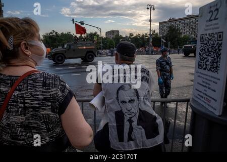 Moskau, Russland. 18. Juni 2020 Menschen beobachten eine gepanzerte Fahrzeuge während einer Generalprobe einer Militärparade anlässlich des 75. Jahrestages des Sieges im Zweiten Weltkrieg, in der Tverskaya Straße in Moskau, Russland. Die Parade 2020, die jährlich am 9. Mai stattfindet, wurde von Russlands Präsident Wladimir Putin für den 24. Juni inmitten der Coronavirus-Pandemie verlegt. Die Inschrift auf der weißen Weste lautet: "Ohne die Unterstützung des Volkes ist es unmöglich zu arbeiten" Stockfoto