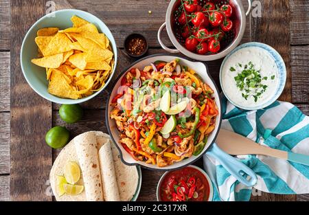 Hühnerfajita in einer rustikalen Pfanne mit hausgemachten Dips Stockfoto