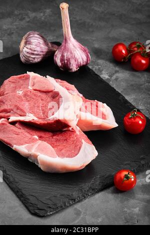 Zwei Stücke Schweinefleisch auf einem Schieferteller auf einem grauen Hintergrund. Kopierraum, Foto für Lebensmittelgeschäfte Stockfoto