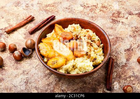 Hirseporridge mit karamellisierten Bananen und Nüssen. Stockfoto