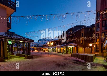 Nachtleben im alpinen Dorf mit traditionellen Holzhäusern, Geschäften und Restaurants Stockfoto