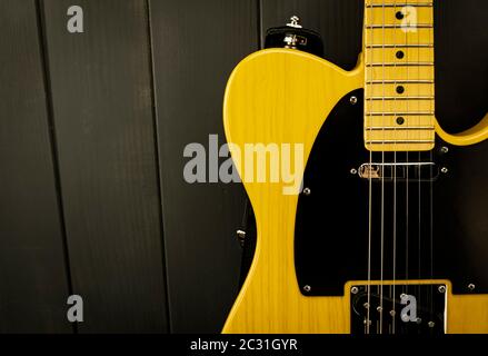 Details einer klassischen E-Gitarre in Gelb und Schwarz mit Bünden, Saiten, Hals und Mikrofon Stockfoto