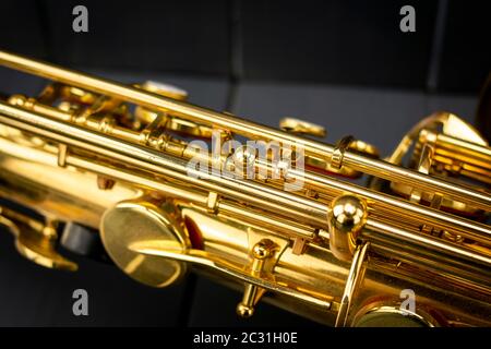 Körper, Stäbe und Schlüssel eines goldenen Saxophons auf grauem Holzhintergrund Stockfoto