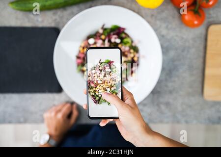 In der Nähe der Frau, die der Aufnahme von Nahrungsmitteln mit Handy Stockfoto