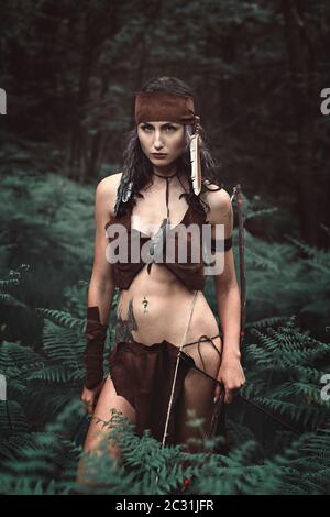 Gefährliche Jägerin posiert mit Bogen im Wald Stockfoto