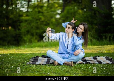 Junges Paar mit Handy ein selfie im Park Stockfoto