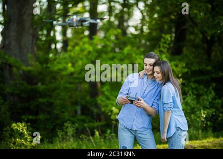 Portrait von Mann und Frau ist die Bedienung der Drohne per Fernbedienung im Park. Mann und Frau spielen mit Quadrocopter im Freien. Stockfoto