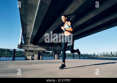 Junge Fitness-Frau läuft am Flussufer Stockfoto