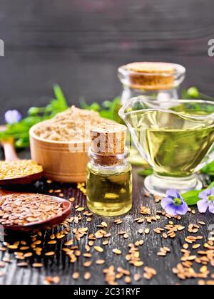 Leinöl in zwei Gläser und eine Sauciere mit weißen und braunen Leinsamen in Löffel Mehl in eine Schüssel, Blätter und Blüten auf Holzbrett backgrou Stockfoto