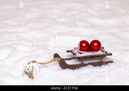 Weihnachten Grußkarte Vorlage. Eine kleine Eisbär zieht einen Schlitten mit zwei roten Weihnachtskugeln durch den Schnee. Kopieren Sie Raum für Ihre Konstruktion. Makro Stockfoto