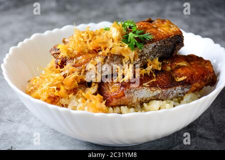 Frittierte scheiben Pangasius Fisch mit Knoblauch, mit braunem Reis serviert. Stockfoto