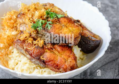 Frittierte scheiben Pangasius Fisch mit Knoblauch, mit braunem Reis serviert. Stockfoto