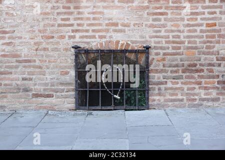 Fenster geschlossen mit einem Metallgitter, in der Fassade eines alten vernachlässigten Hauses, in einer süditalienischen Kleinstadt Stockfoto