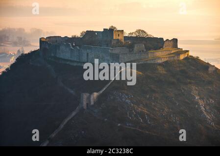 Ruine der Burg auf dem Hügel bei Sonnenaufgang. Schlossberg in Hainburg an der Donau, Österreich bei Sonnenaufgang vom Hundsheimer Berg. Stockfoto