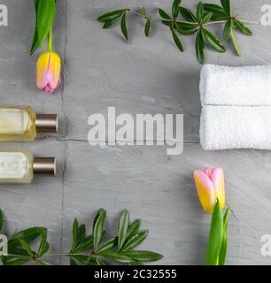 Schmuck, Armband mit Schlüsselanhänger und goldenen Ohrringen zusammen mit Tulpen und grün auf einem Betongrund gelegt. Innerhalb der Komposition, freier Raum. Stockfoto