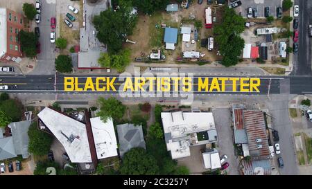 Austin, TX USA 18. Juni 2020: City of Austin in Austin, Austin, Texas, werden gelbe Buchstaben mit der Aufschrift "Black Artists Matter" in der historisch schwarzen Nachbarschaft der East 11th Street gemalt, nachdem eine Koalition von Künstlern und Aktivisten das Wandbild fertig gestellt hat. Das Gemälde kam zwei Tage nachdem die gleiche Gruppe "Black Austin Matters" auf Austin's Main Street, Congress Avenue gemalt hatte.Quelle: ATXN via Bob Daemmrich/Alamy Live News Stockfoto