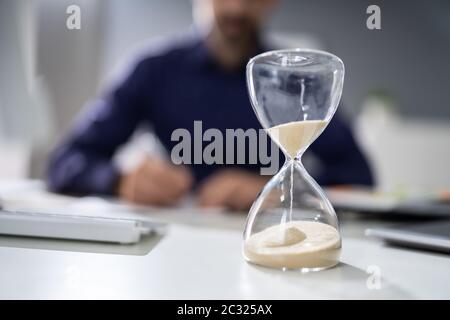 Nahaufnahme der Sanduhr Vor dem Unternehmer Hand Berechnung Rechnung Stockfoto