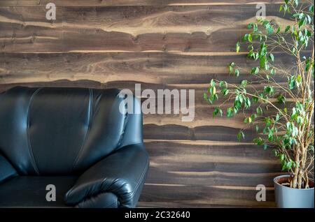 Schwarzer Ledersessel neben dem Heimatbetrieb im Innenraum. Stockfoto