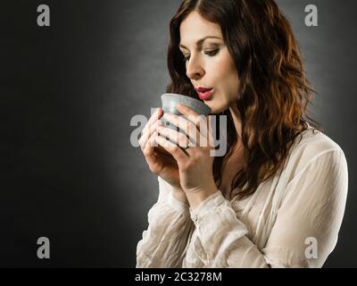 Schöne happy rothaarige Frau Blasen auf ihrem heißen Kaffee. Stockfoto