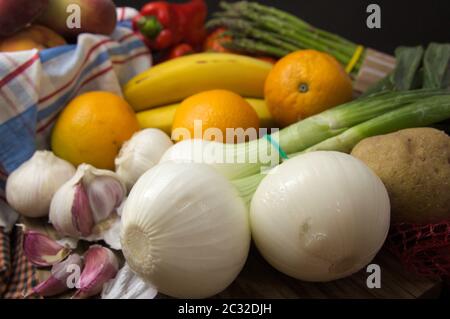 Nahaufnahme einer Stillzeit von pflanzlichen Produkten wie Zwiebeln, Knoblauch, Bananen, Paprika, Spargel, Orangen, Kartoffeln, Pfirsiche Stockfoto