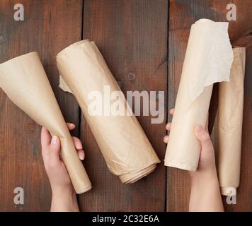 Vier gerollte Brötchen von Braunem pergament Papier auf einer hölzernen Oberfläche, Ansicht von oben Stockfoto