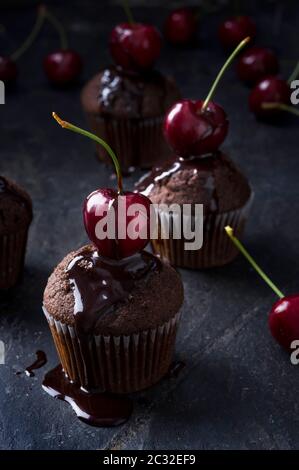 Schokoladenmuffin mit frischen Kirschen und Schokoladensauce auf einer Steinoberfläche Stockfoto