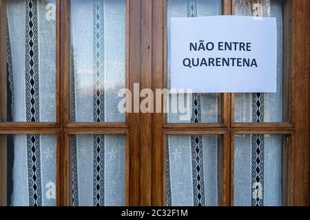 Ein Schild mit der Aufschrift nicht betreten, Quarantäne in portugiesischer Sprache an einem Fenster angebracht Stockfoto