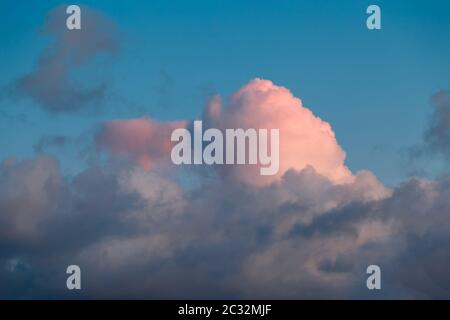 Ungewöhnliche Sonnenuntergangswolken mit rosa Rändern gegen einen blauen Himmel Stockfoto