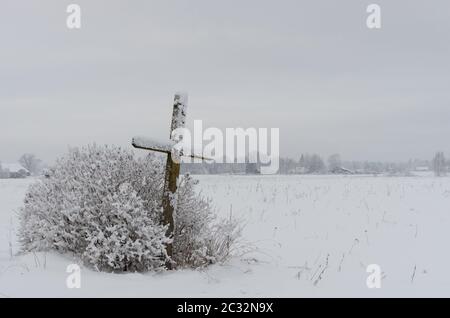 Alten verwitterten hölzernen katholische überqueren auf einer schneebedeckten Wiese Stockfoto