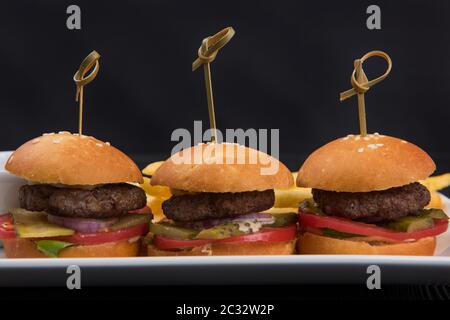 Drei mini Hamburger, mini Burger closeup auf Platte auf dunklem Hintergrund Stockfoto