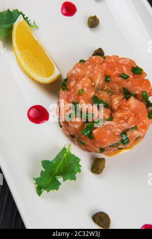 Frisches Lachstatar mit Kalk und Kapern auf weiße Platte Stockfoto