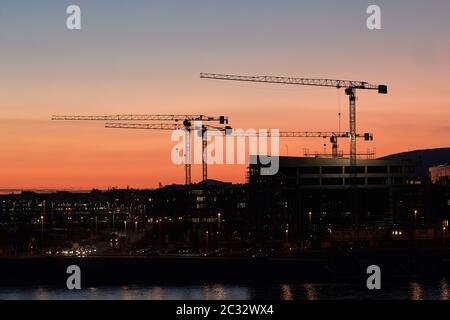 Baukräne gegen dramatische Dämmerung rot glühen Himmel Stockfoto