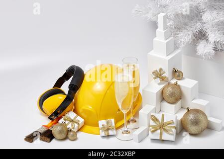 Konstruktion Schutzohrhörer und Schutzhut, Tannenbaum, Flöten mit Champagner, Geschenkboxen und Weihnachtsschmuck auf weißem Hintergrund. Neujahr und Stockfoto