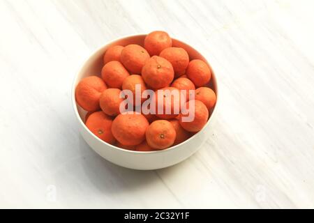 Schüssel mit Mandarinorangen in weißer Schüssel auf der Marmorkonteroberseite Stockfoto