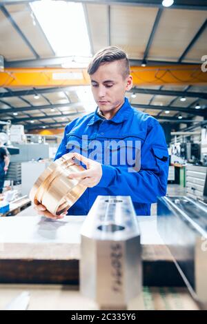 Lehrling in der Metallbearbeitung, der sich anschaut, dass das Werkstück zufrieden ist Stockfoto