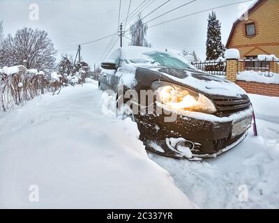 Schwarzes Heckklappe Auto in großen Schneewehe stecken. Probleme mit dem Wintertransport. Gefrorenes Auto. Stockfoto