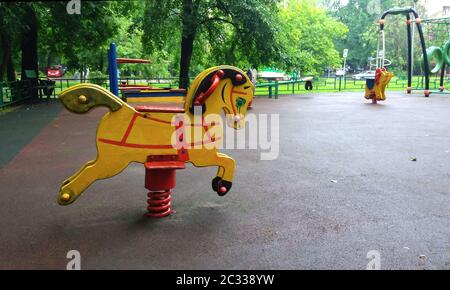 Leerer Kinderspielplatz in Wohngebiet, Schaukelpferd im Sommerhof Stockfoto