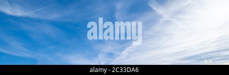 Weiße flauschige Cirrus- und Cirrocumulus-Wolken in tiefblauem azurblauen Himmel und Sonnenlicht leuchten am Himmel Stockfoto