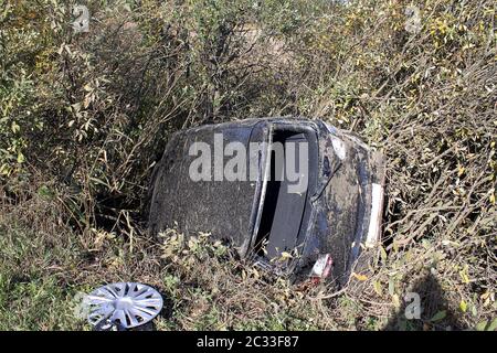 Totaler Autounfall auf dem Higway. Rückseite des Autos ohne Fenster. Das Auto in den Büschen flog von der Bordsteinkante. Stockfoto