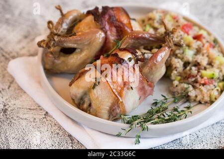 Köstliche gebackene Wachteln mit Speck und Beilage. Stockfoto