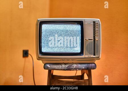 Vintage-Fernseher auf einem Stuhl in einem leeren Raum Stockfoto