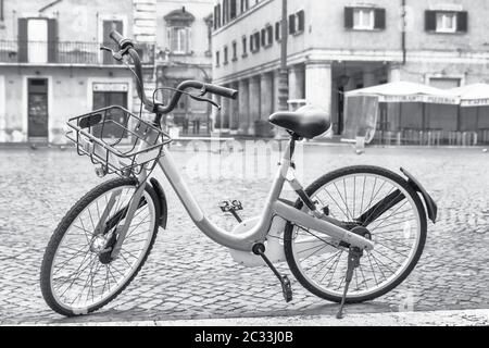 Schwarz-Weiß-Foto eines Fahrrads, das auf dem leeren Navona-Platz in Rom zum Mitmachen bereit ist. Italien. Alle potenziellen Marken werden entfernt. Stockfoto