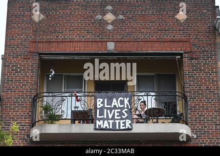 Hoboken, USA. Juni 2020. Eine Frau, die vor ihrer Wohnung sitzt, zeigt ein Banner mit dem Titel „Black Lives Matter“, das an der Geländer ihres Balkons angebracht ist, in Hoboken, NJ, 18. Juni 2020. Nach Monaten der Stilllegung von COVID-19, um die Ausbreitung des tödlichen Virus zu verhindern, erlauben neue Stadtverordnungen Unternehmen, Gehwegsflächen zu nutzen, um die Gastronomie-Shopping-Öffentlichkeit zu bedienen.(Anthony Behar/Sipa USA) Kredit: SIPA USA/Alamy Live News Stockfoto