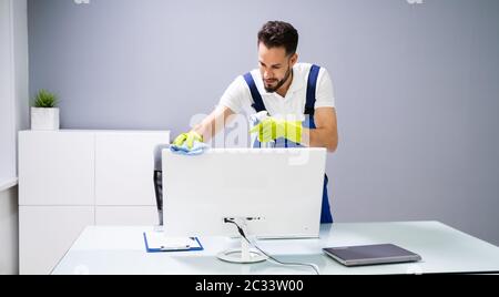 Portrait Des Computers Zur Reinigung Des Männlichen Hausmeisters Am Schreibtisch Stockfoto