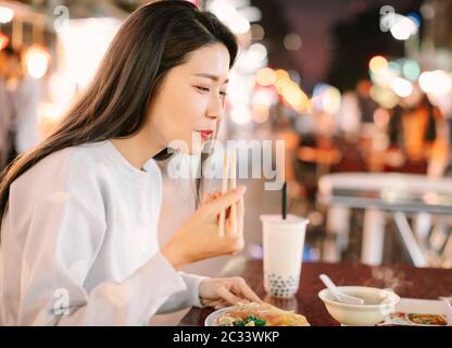 Asiatische Frau genießen bubble Milch Tee mit Street Food in der Nacht Markt Stockfoto